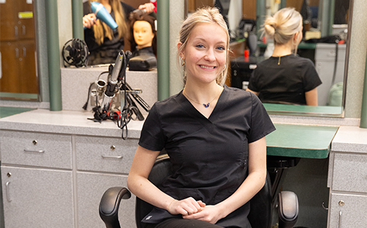 Cosmetology student smiles sitting in chair